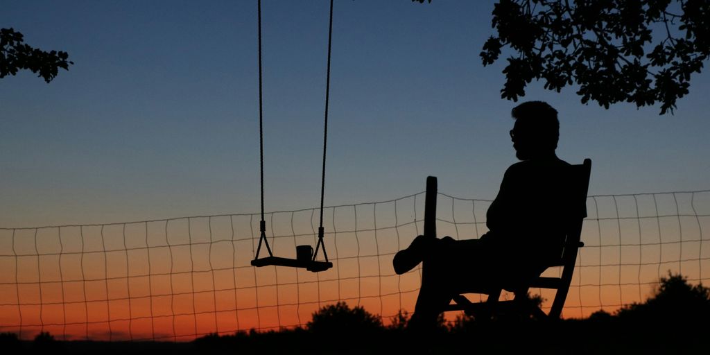 a man sitting in a chair next to a swing