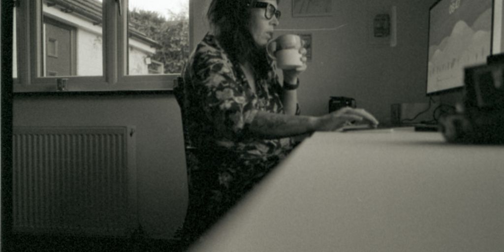 a woman sitting at a desk with a cup of coffee