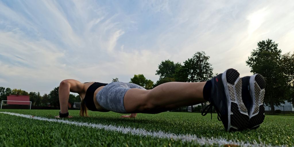 a woman is doing push ups on the grass