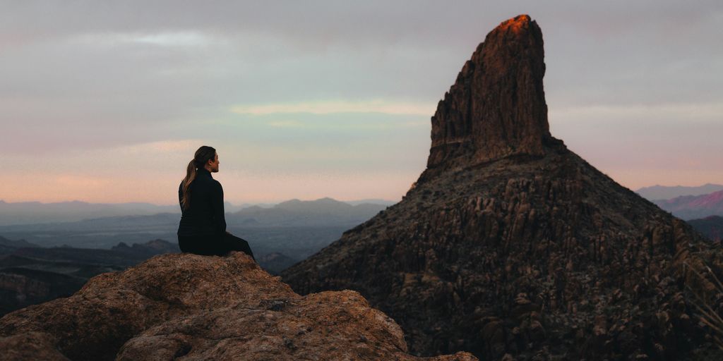 a woman sitting on top of a large rock