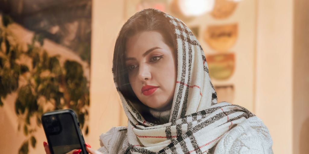 a woman in a scarf looking at a cell phone