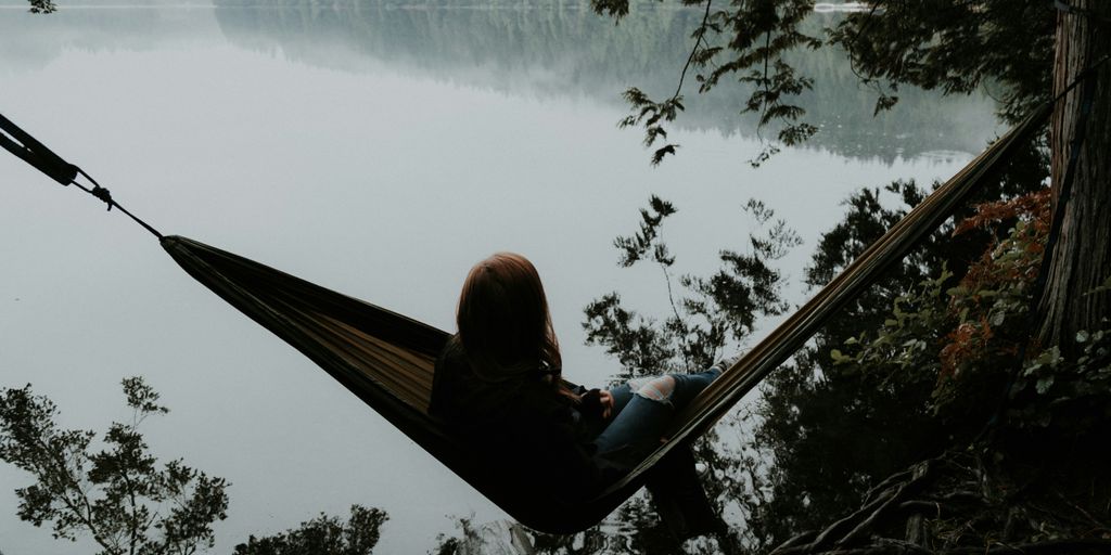 woman sitting on hammock while facing backwards