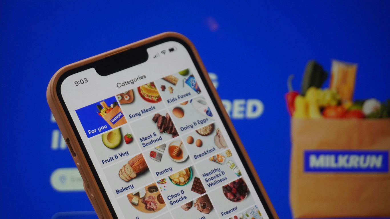 A person holding a cell phone in front of a screen