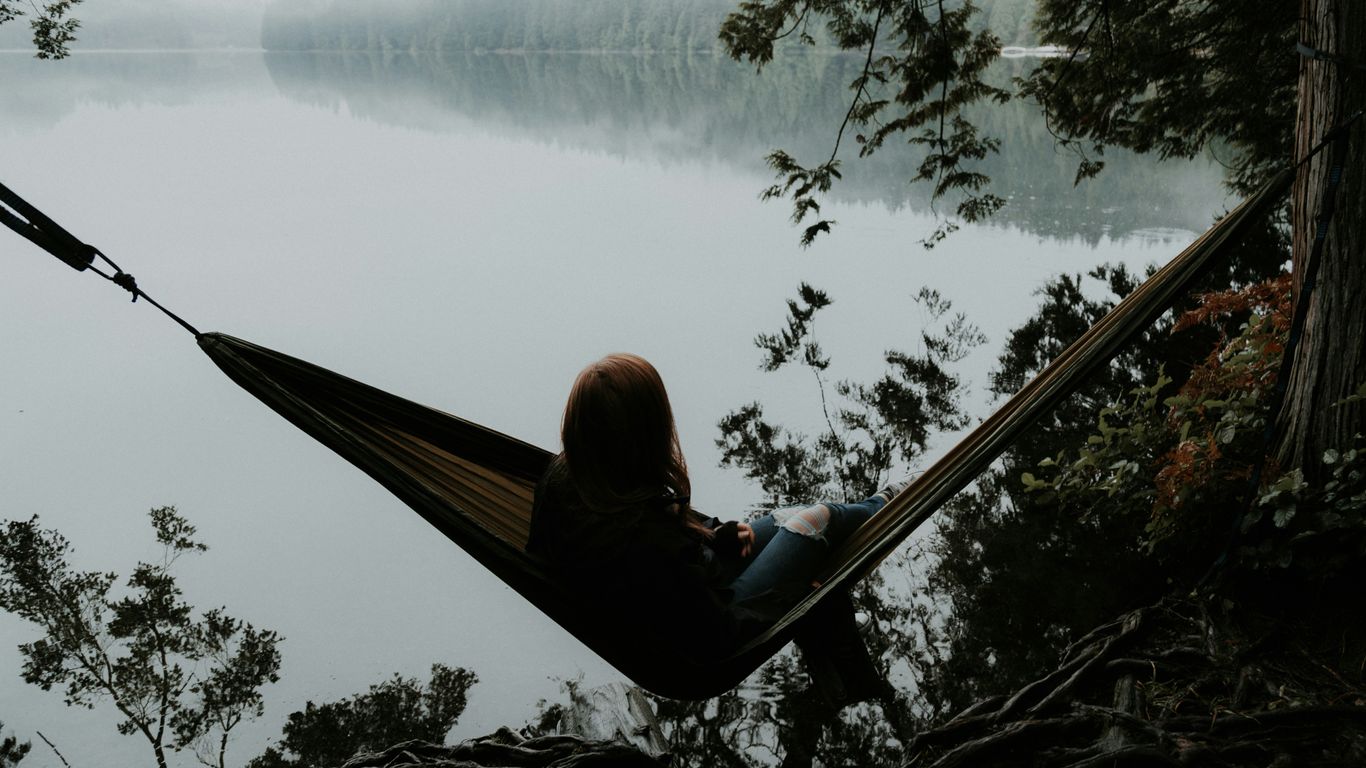 woman sitting on hammock while facing backwards
