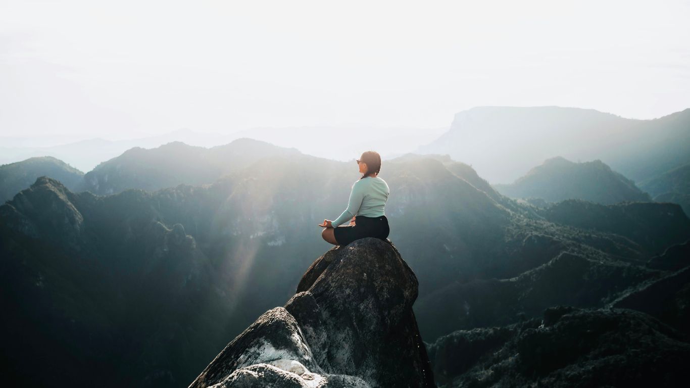 a man sitting on top of a large rock