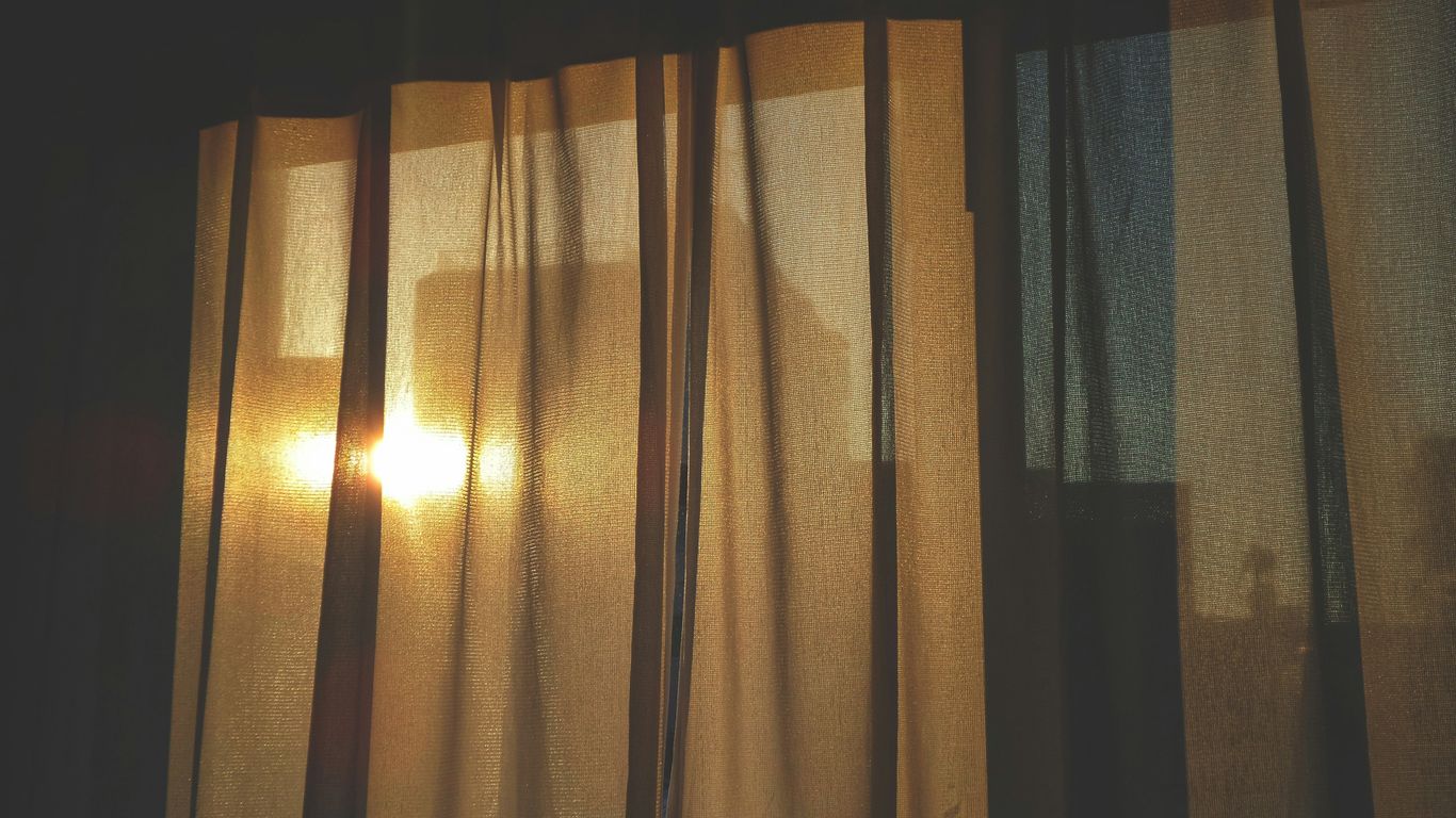 the sun is shining through the curtains of a window