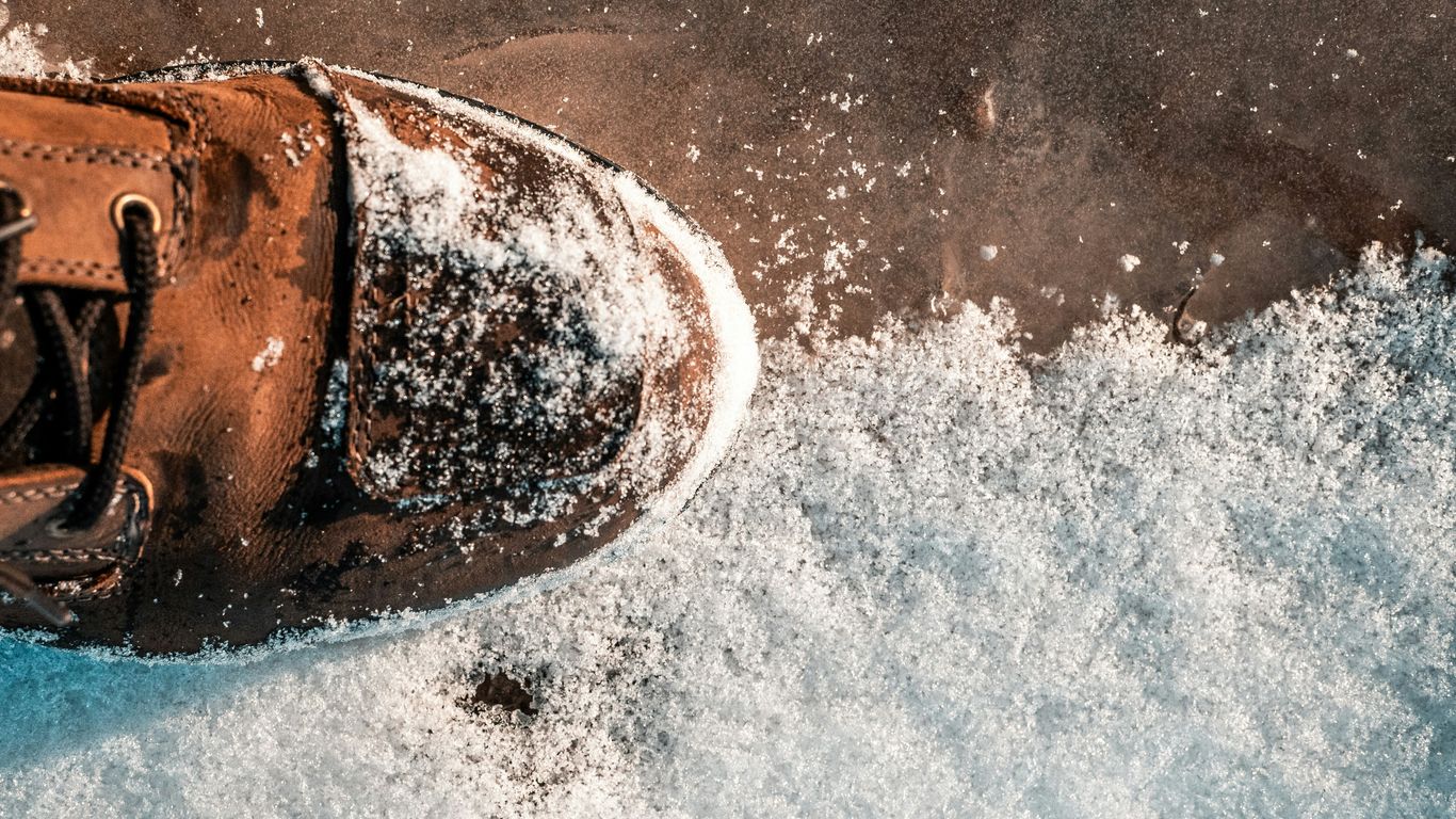 a pair of brown shoes sitting on top of a pile of snow