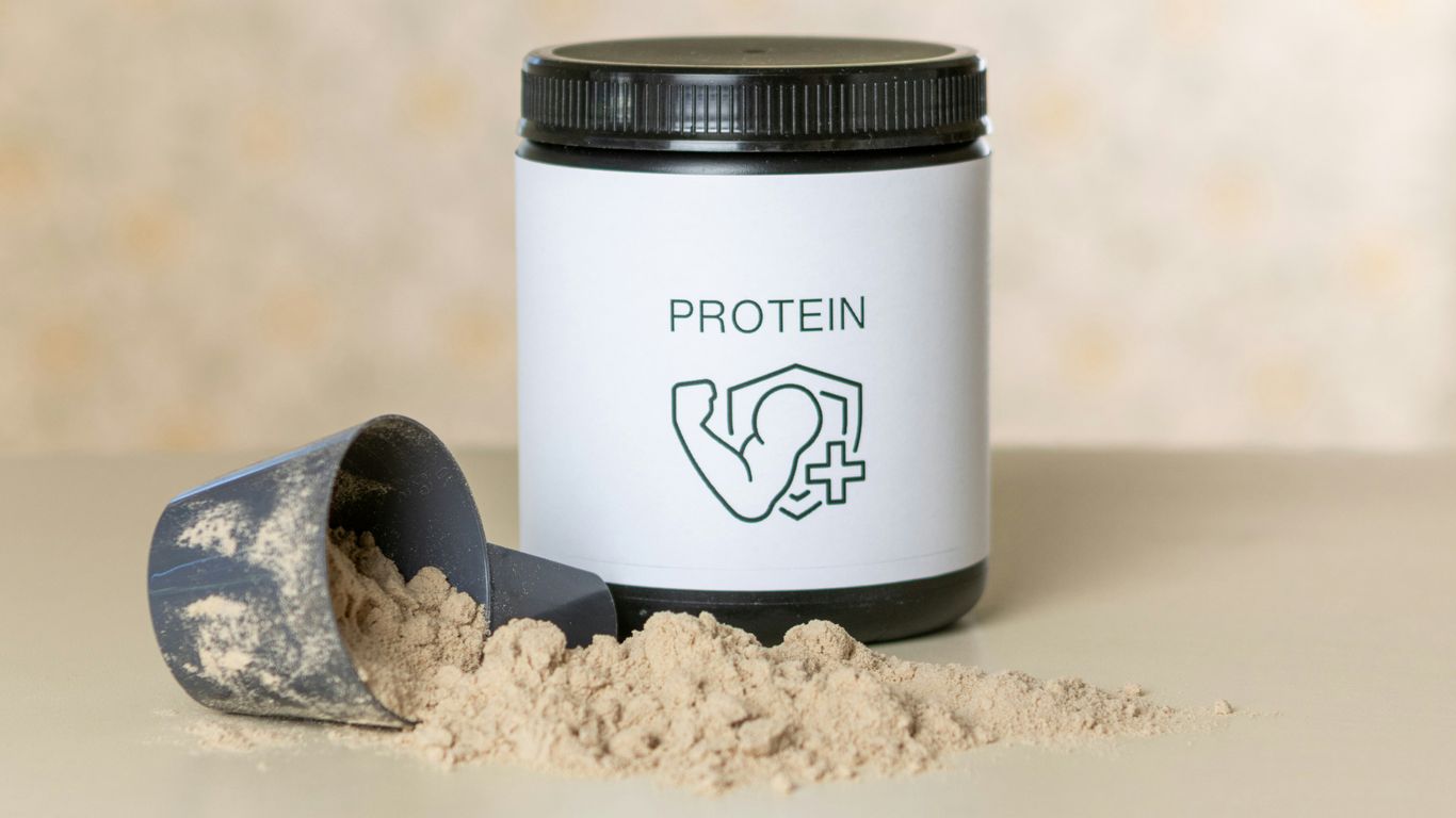 a jar of protein powder next to a scoop of powder