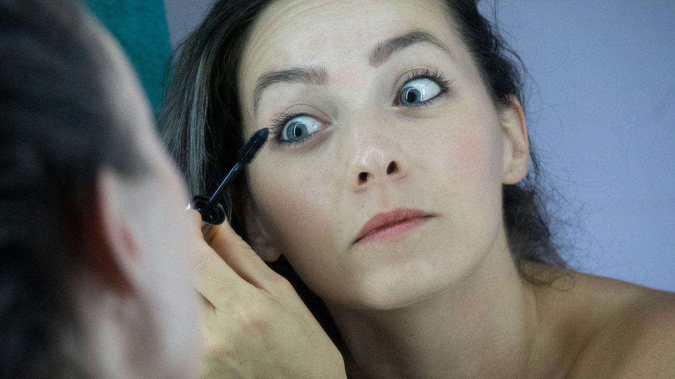 a woman is putting mascara on her face