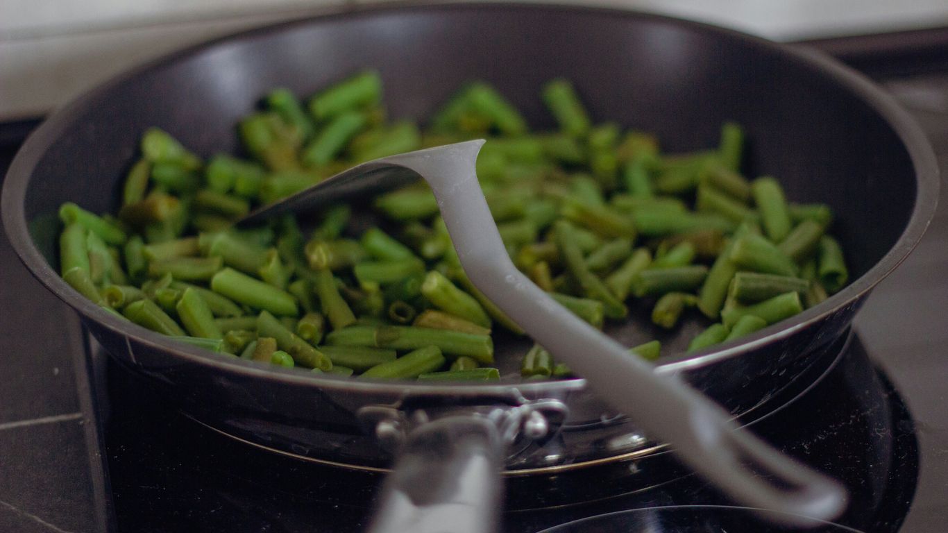 A pan filled with green beans on top of a stove
