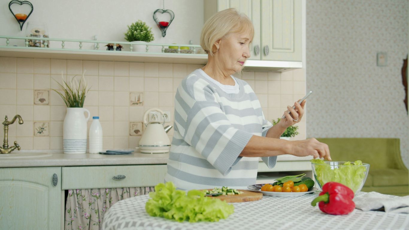 Elderly woman preparing salad in a kitchen
