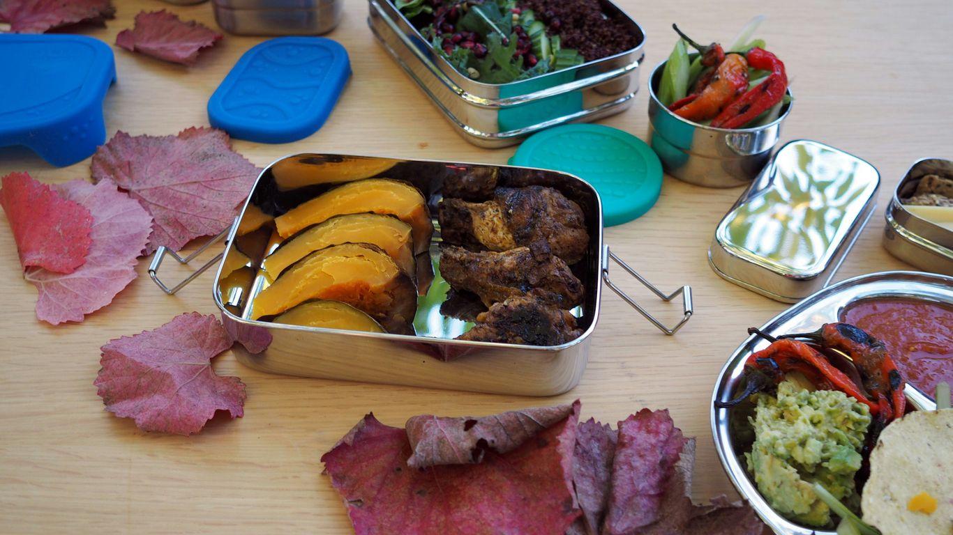 a wooden table topped with metal containers filled with food