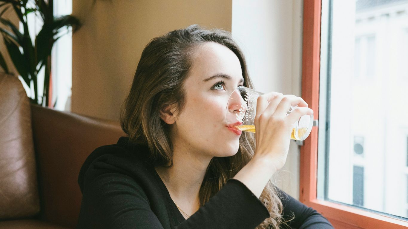 woman sipping beverage on drinking glasses indoors