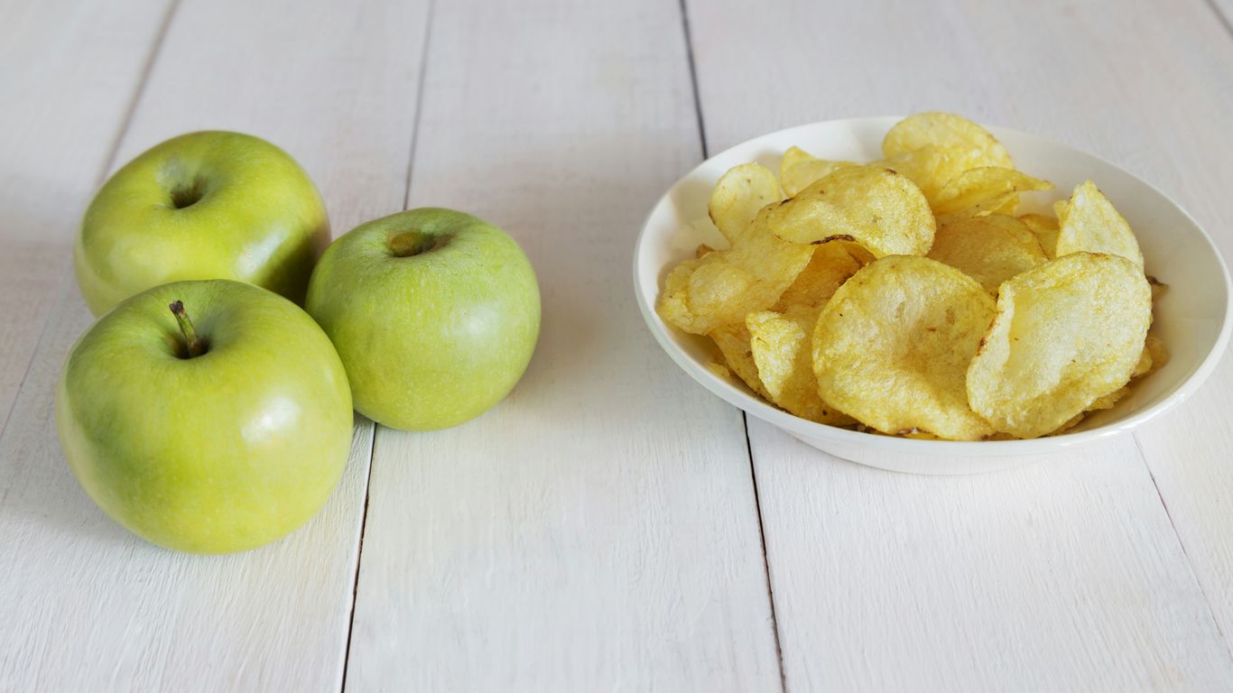 a bowl of chips next to a bowl of apples