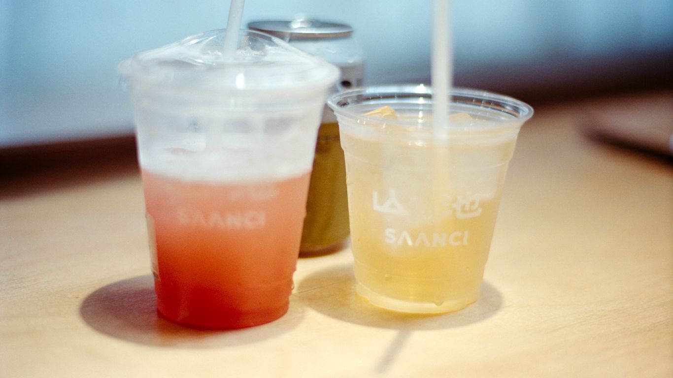 Two colorful drinks with straws and a small can.