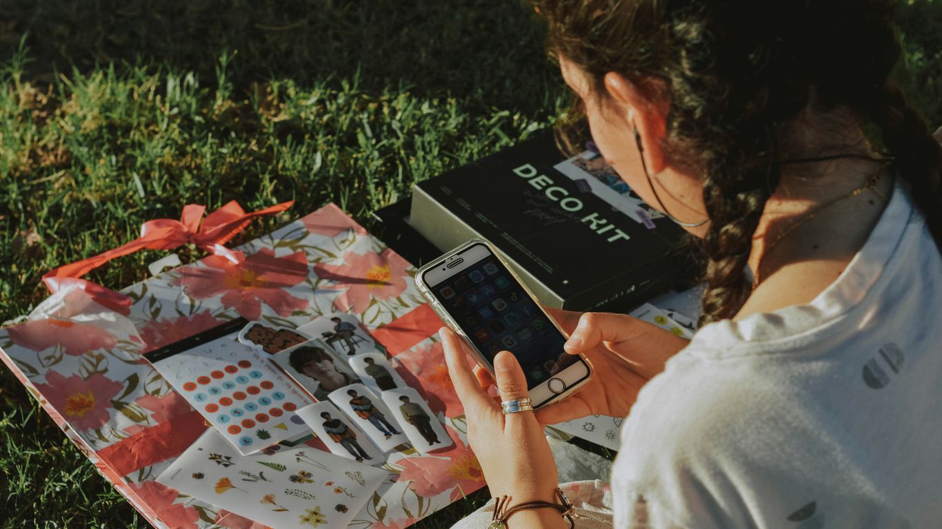 a woman sitting in the grass looking at her cell phone