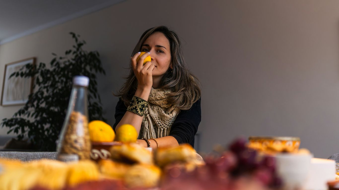Woman smelling a lemon at a table with food