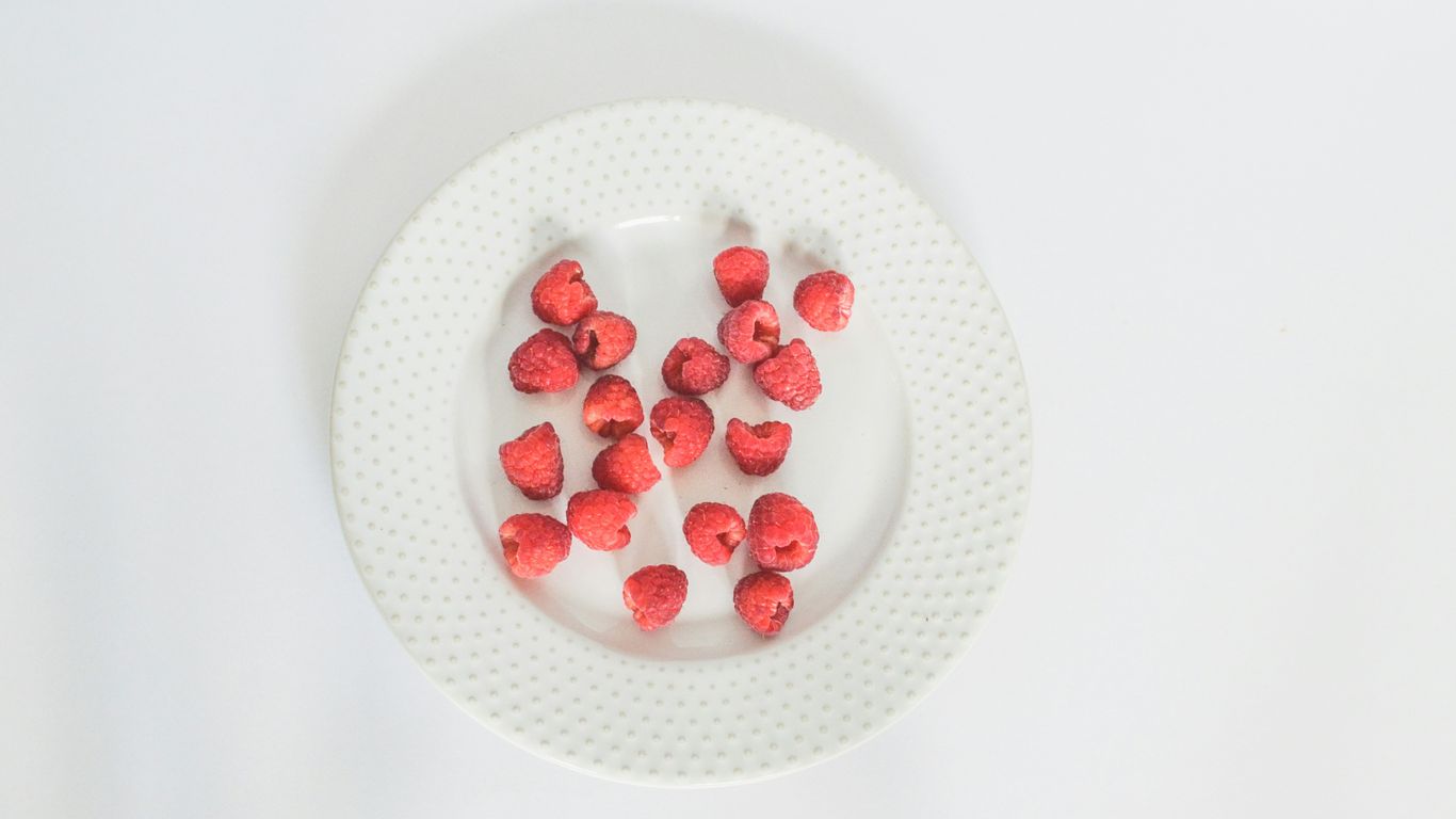 a white plate topped with strawberries on top of a white table