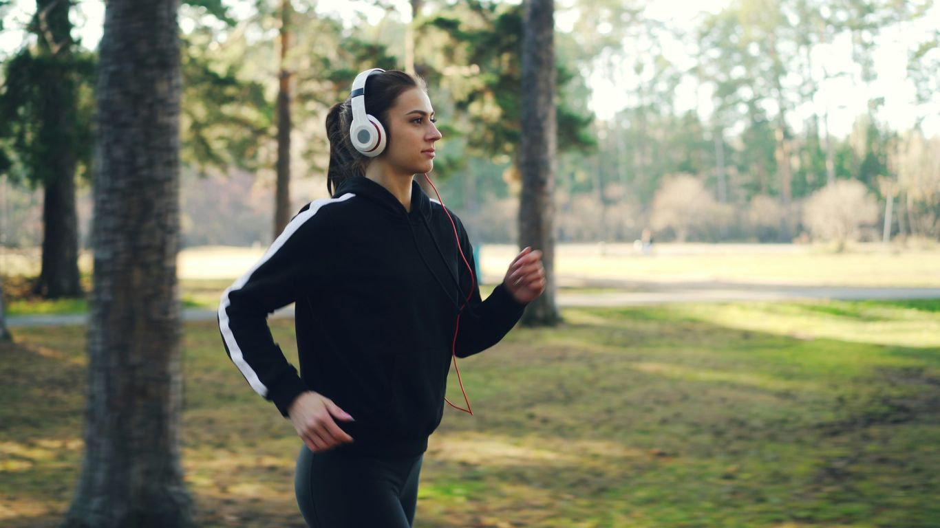 Young woman jogging in park with headphones on