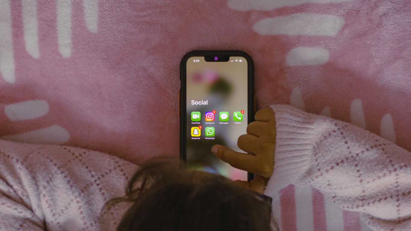 a person laying in bed holding a cell phone