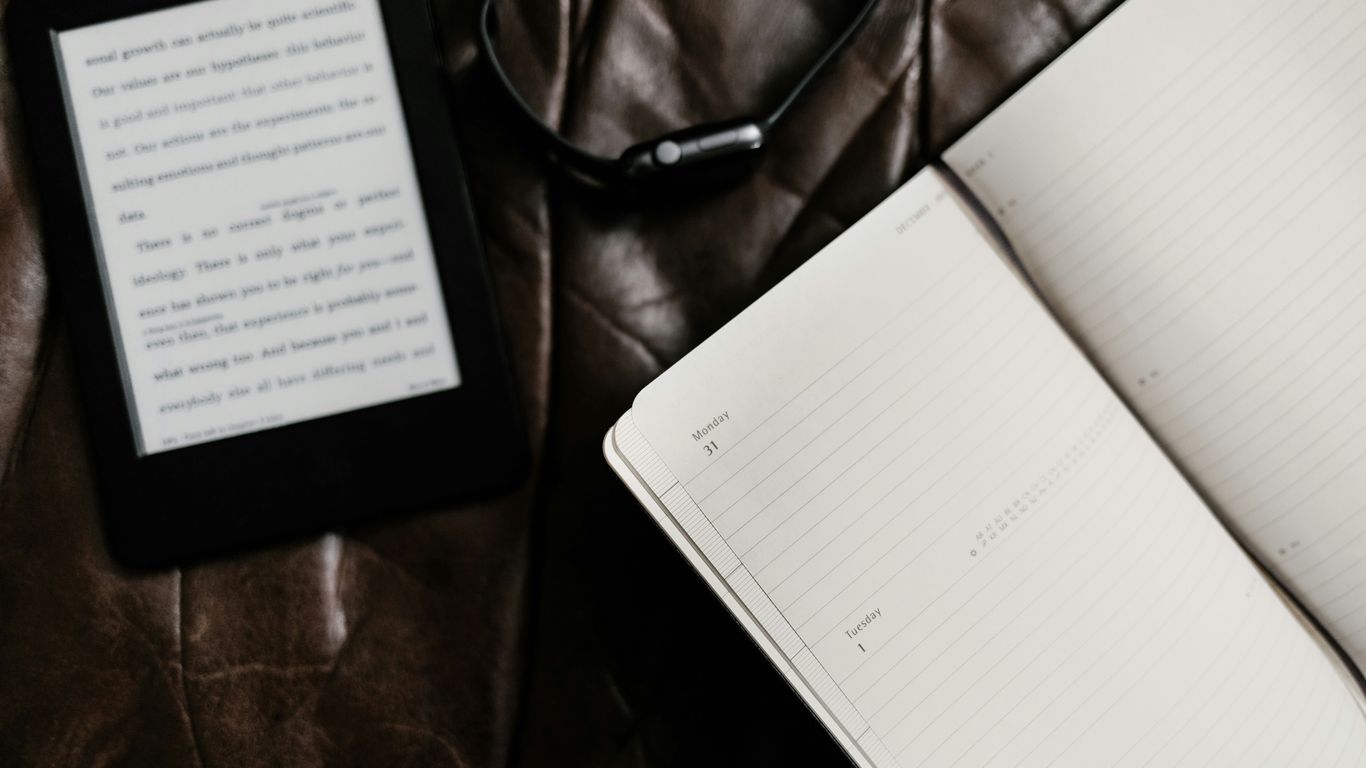 black e-book reader beside open book