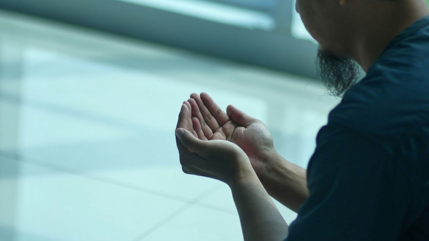 a man sitting on the ground with his hands together