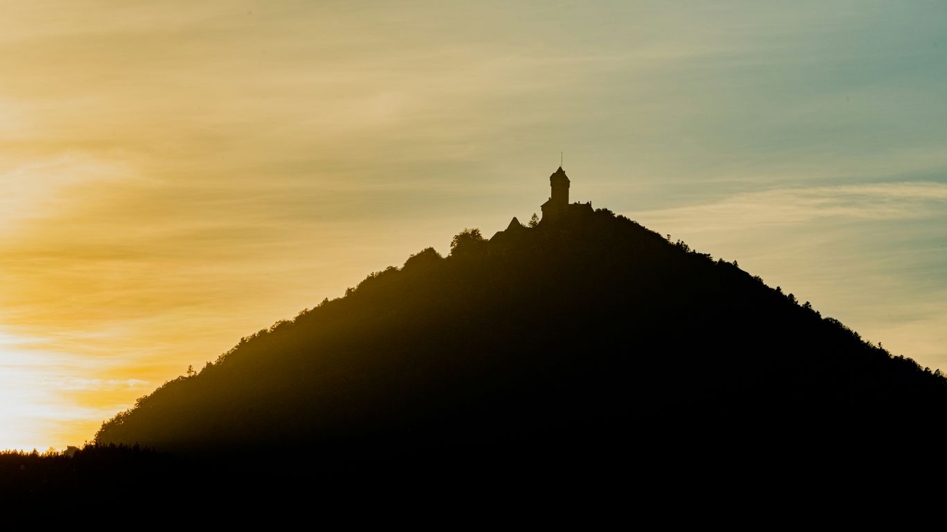 a silhouette of a hill with a clock tower on top
